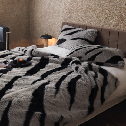 Zebra gray faux fur throw blanket layered on bed with modern neutral tones and soft fluffy texture