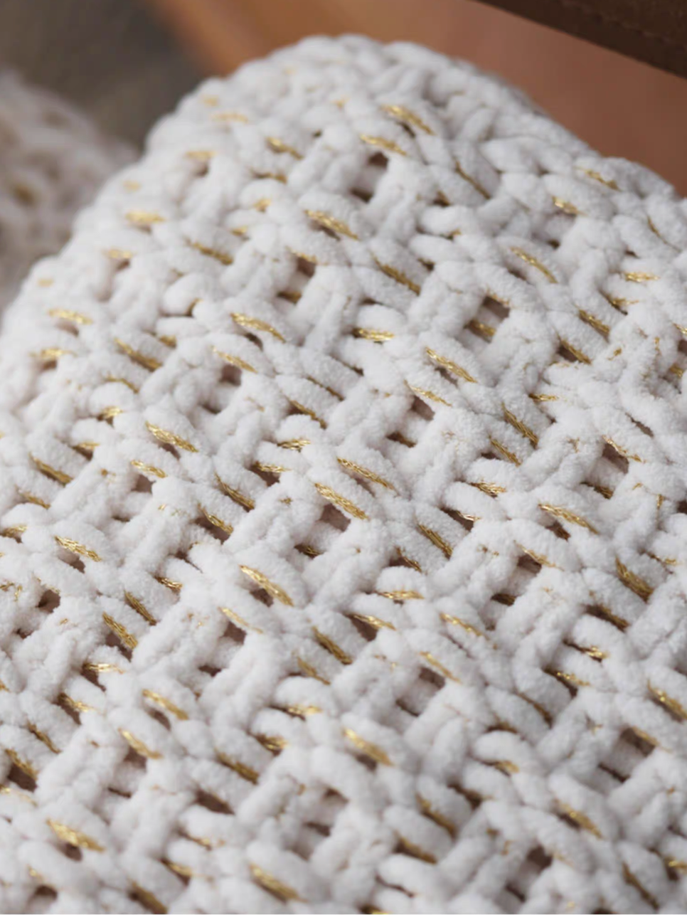 Macro close-up of white chunky knit throw blanket with soft chenille yarn and subtle gold thread detail