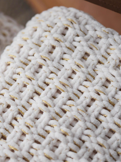 Macro close-up of white chunky knit throw blanket with soft chenille yarn and subtle gold thread detail