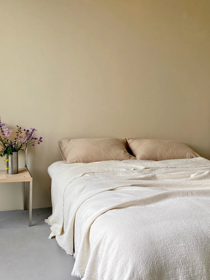 Close up of ivory white French flax linen duvet thin quilt fabric texture highlighting breathable crinkled linen weave