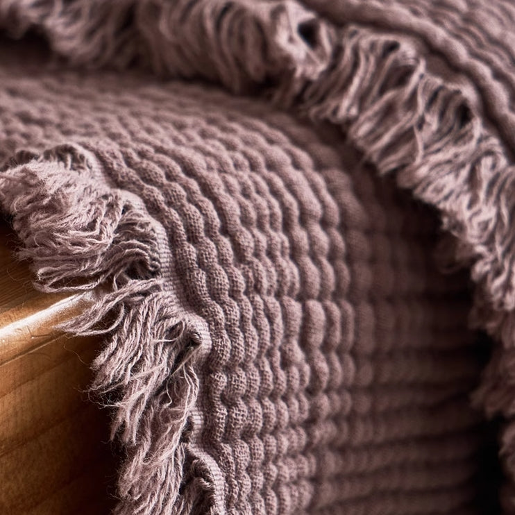 Mocha purple waffle textured organic cotton throw blanket close-up highlighting woven gauze texture and fringe.