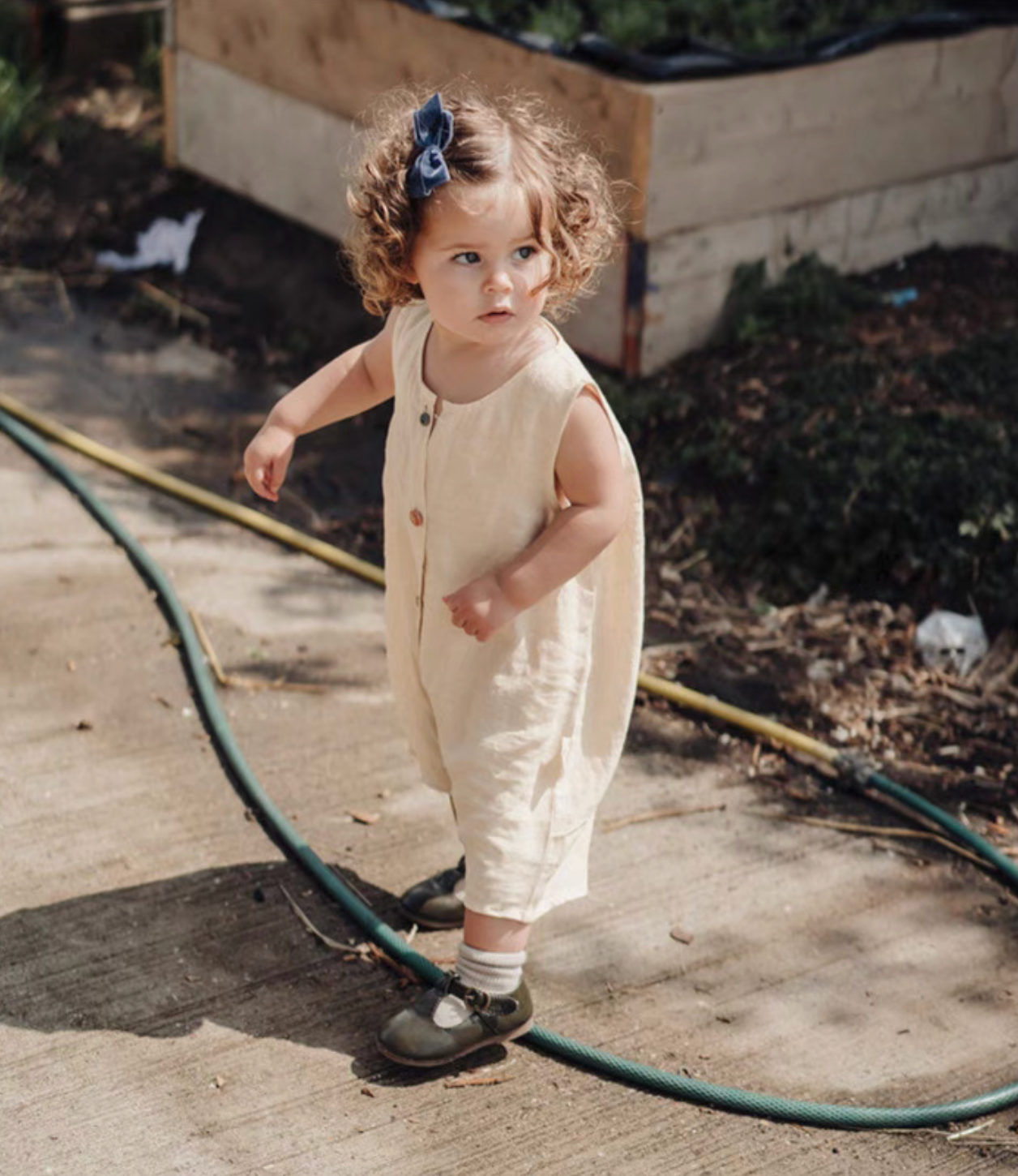 Toddler wearing peach sleeveless cotton baby romper with button front soft breathable summer outfit full body view