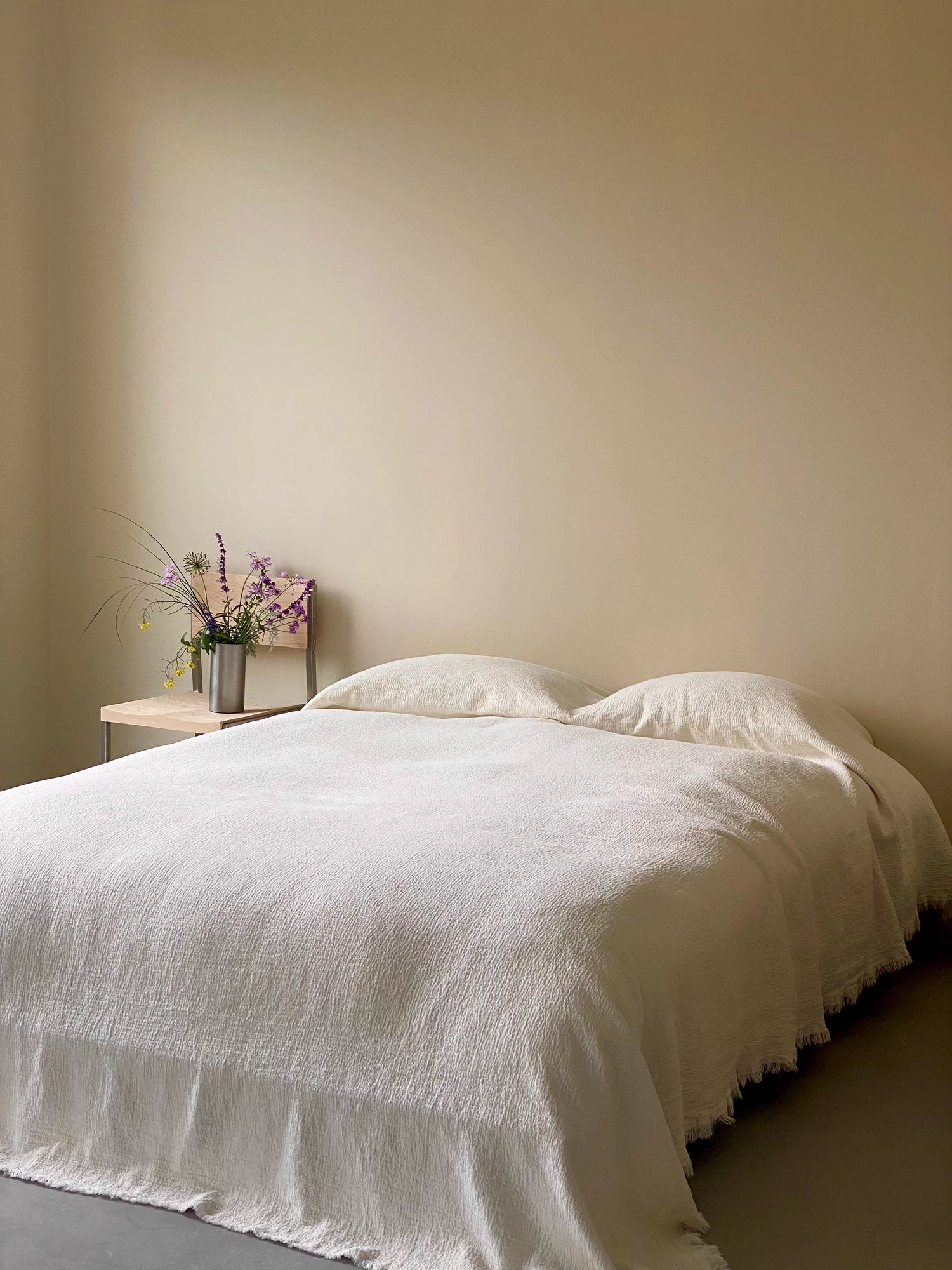 Stonewashed ivory white French flax linen duvet thin quilt draped across bed showing natural breathable linen bedding