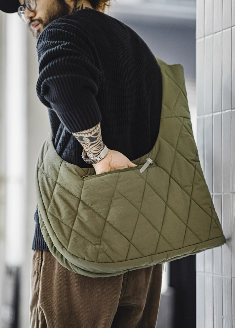 Side view of olive vest converted into crossbody bag showing functional zip pocket.