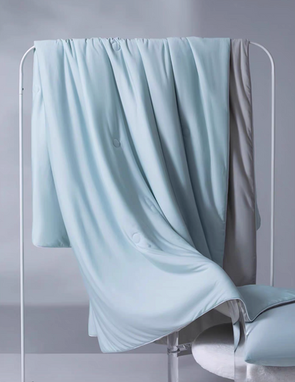 Blue and gray reversible cooling summer quilt hanging on a rack, displaying soft antibacterial cooling fabric texture.