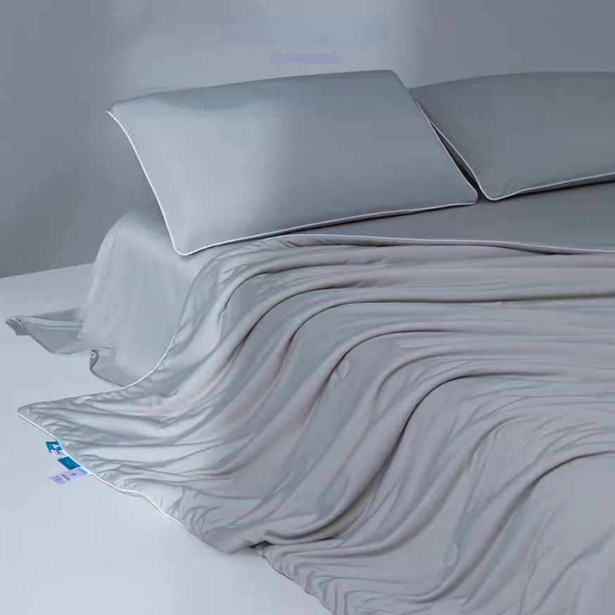 Gray cooling antibacterial summer comforter spread across a bed with soft pillows highlighting smooth cooling yarn fabric.