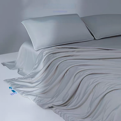 Gray cooling antibacterial summer comforter spread across a bed with soft pillows highlighting smooth cooling yarn fabric.