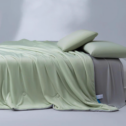 Green and gray cooling summer comforter layered across a bed with soft pillows, designed for breathable summer sleep.