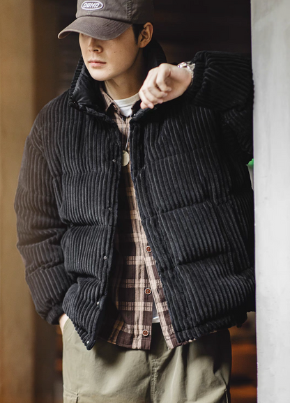 Black corduroy down jacket layered over plaid shirt demonstrating casual streetwear styling and warmth