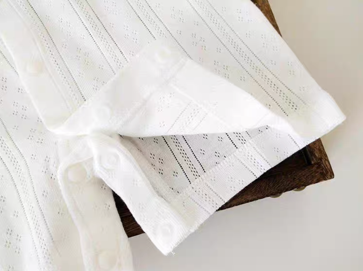 Close-up of white baby romper leg opening with snap button closure for easy diaper change