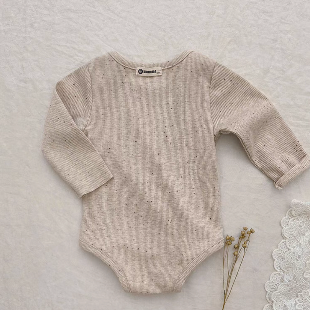Back view of oatmeal beige baby bodysuit highlighting soft breathable fabric texture