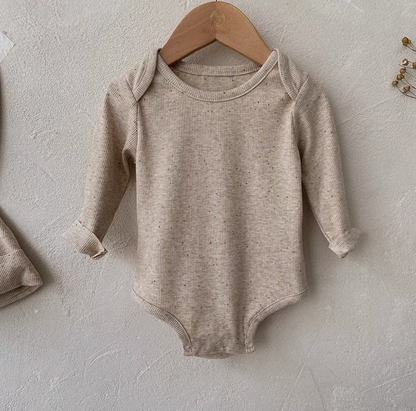 Close-up front view of oatmeal beige long sleeve baby bodysuit showing ribbed cotton fabric