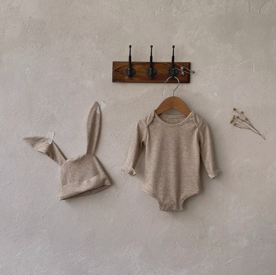 Oatmeal beige long sleeve baby bodysuit with bunny ear hat minimal wall hanging display