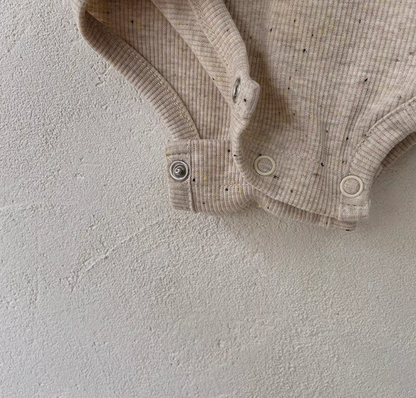 Close-up of snap button bottom on oatmeal beige baby romper for easy diaper change