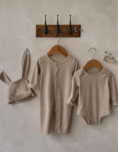 Oatmeal beige long sleeve short baby romper set with bunny ear hat hanging on wall display