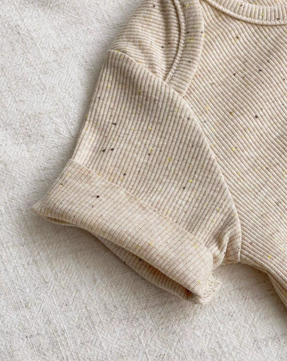 Close-up of oatmeal beige baby romper sleeve showing soft breathable cotton texture