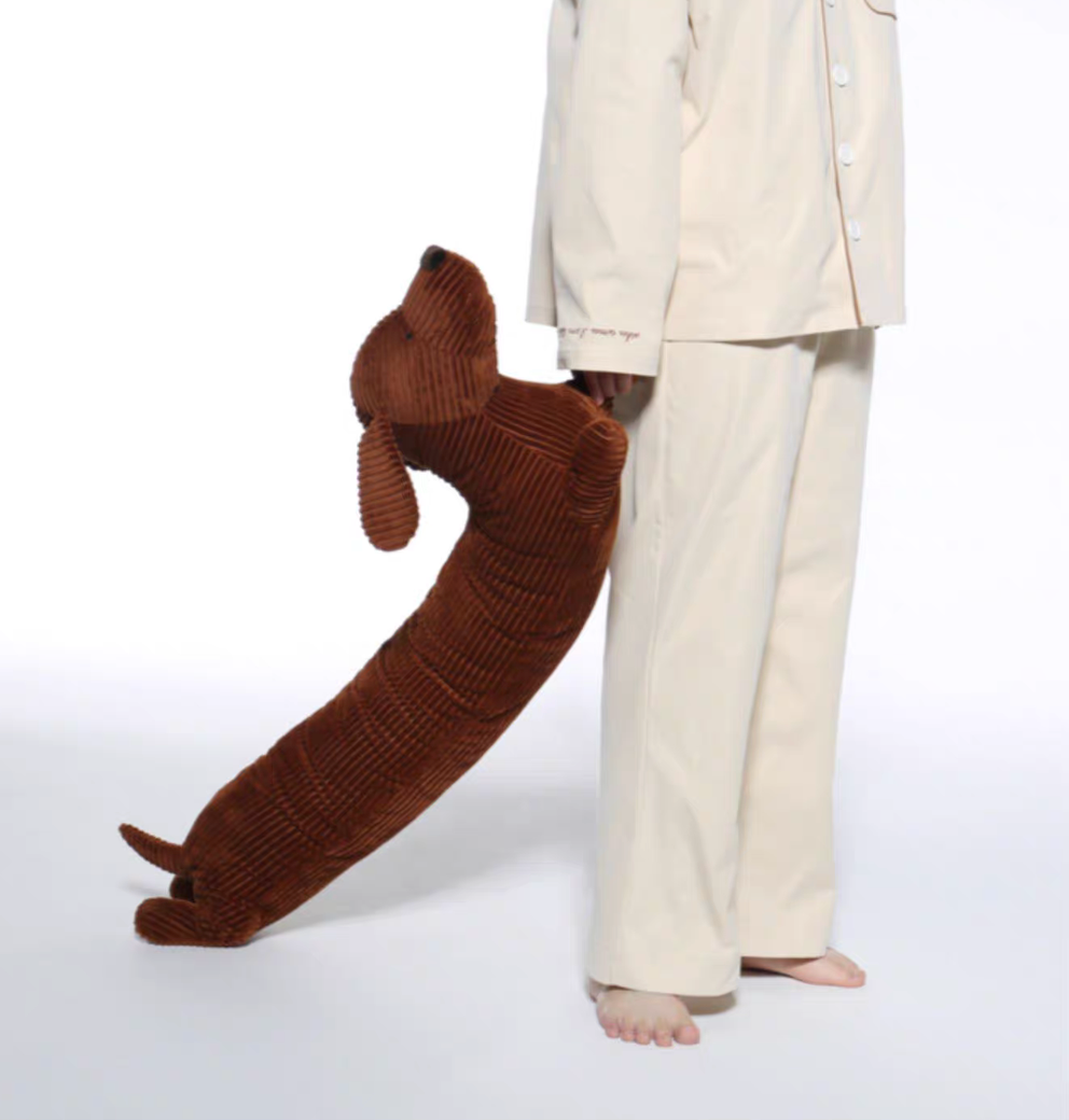 Brown dachshund long body pillow being held downward showing full length and flexible body design