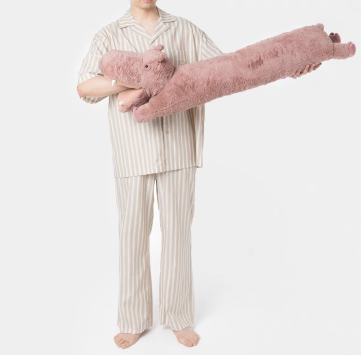 Pink hippo long body pillow held horizontally showing full plush body and soft texture