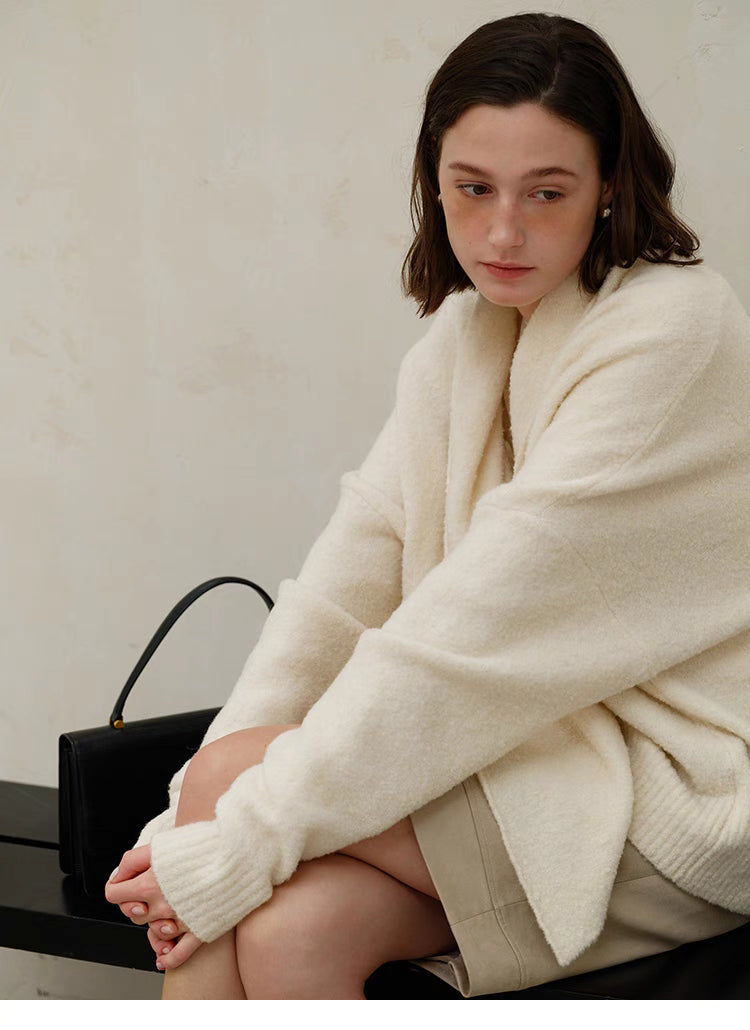 Seated styling of Cozy Elegance Oversized Knit Cardigan in Ivory featuring soft wool blend texture, relaxed silhouette, and cozy comfort