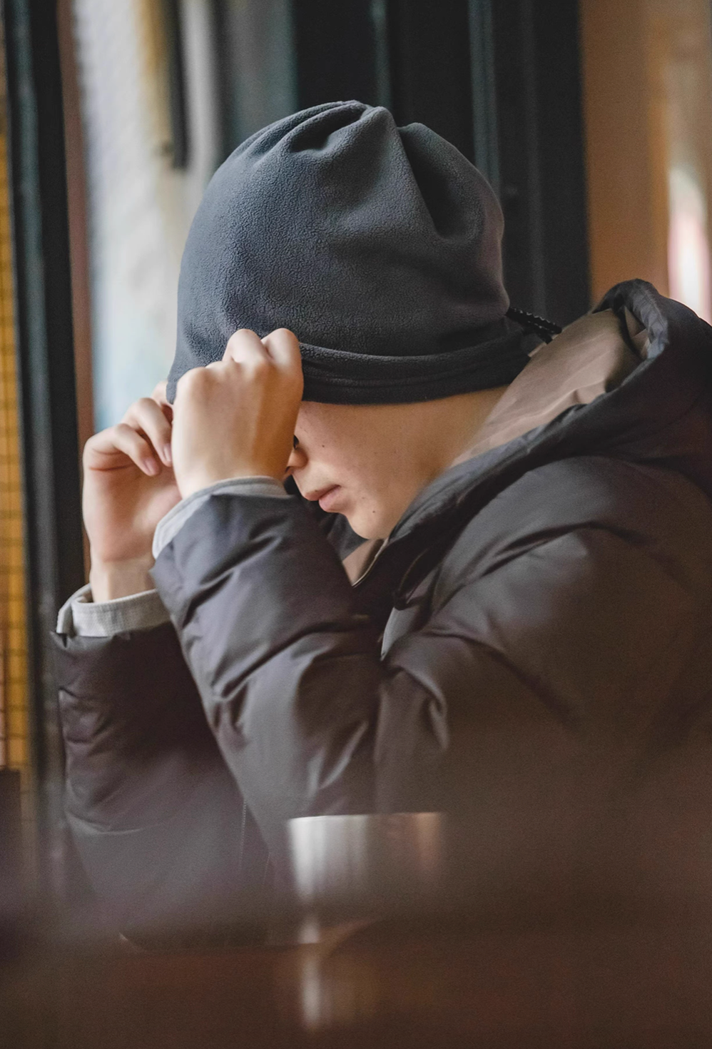 Cozy Magic Neck-Warmer in gray worn by model adjusting the fit, showcasing soft fleece texture and snug coverage in a winter setting