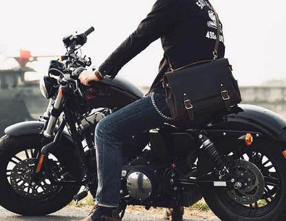 Man on motorcycle wearing brown crazy horse leather satchel across shoulder.