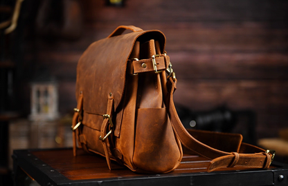 Side angle of brown leather satchel showing side pocket and adjustable strap buckle.