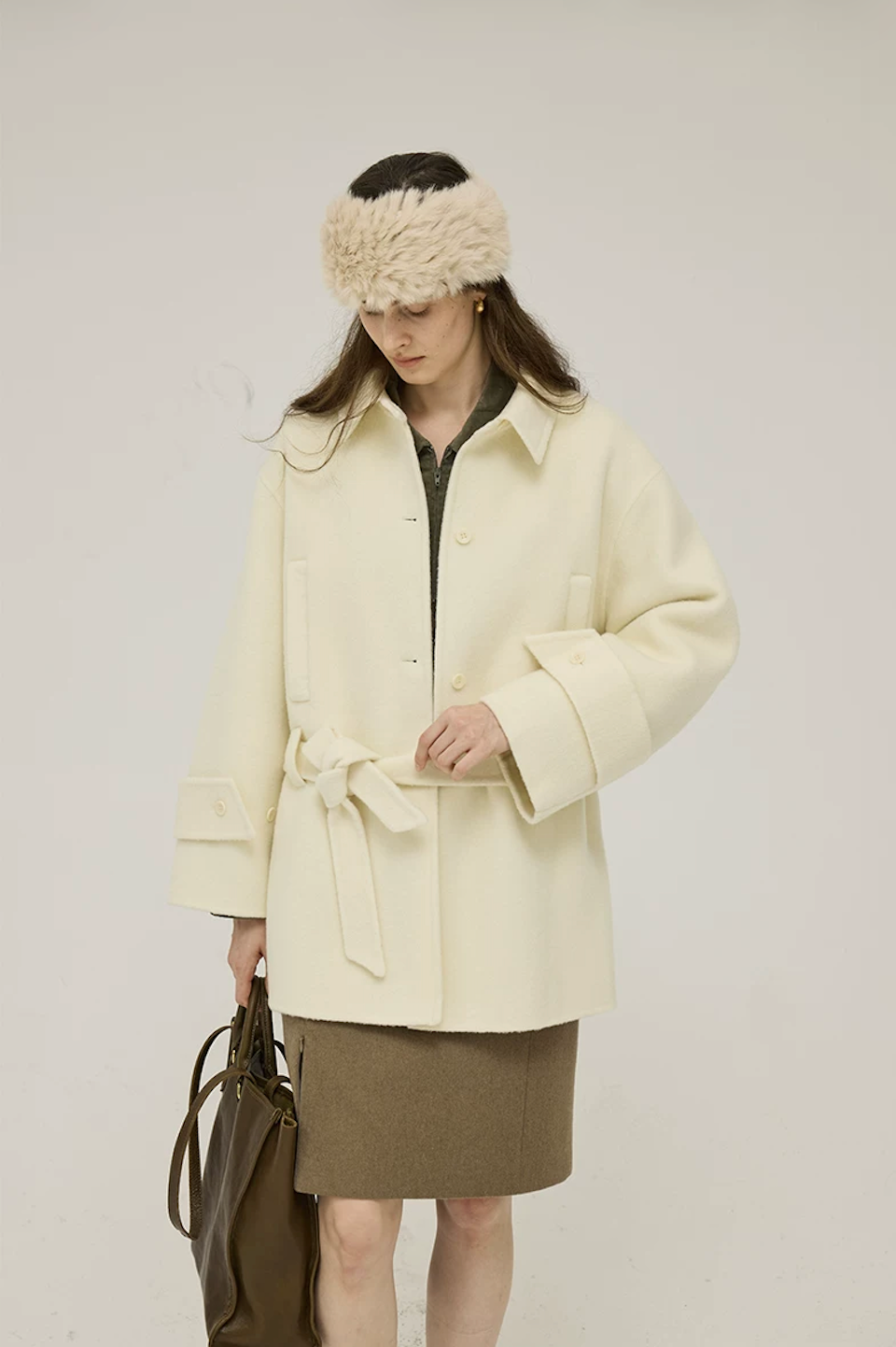 Cream short wool coat tied at the waist, showing the buttoned cuff tab