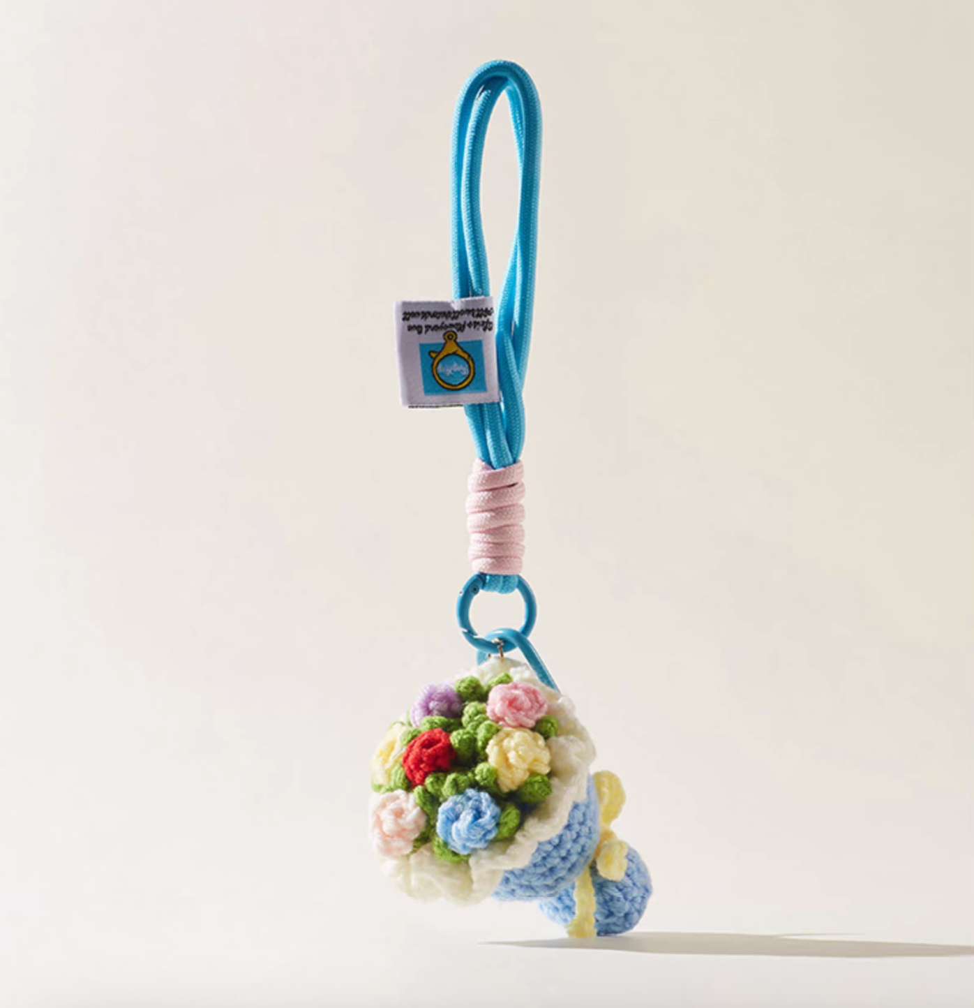 Blue crochet bouquet keychain with pastel flowers and pink rope accent.