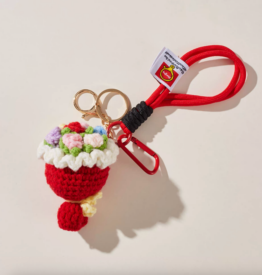 Handmade red crochet flower bouquet keychain with rope loop, gold keyring and red mini carabiner, displayed on a neutral background.