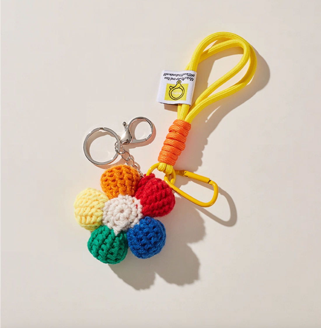 Handmade crochet daisy keychain with yellow cord loop, artisan-crafted.