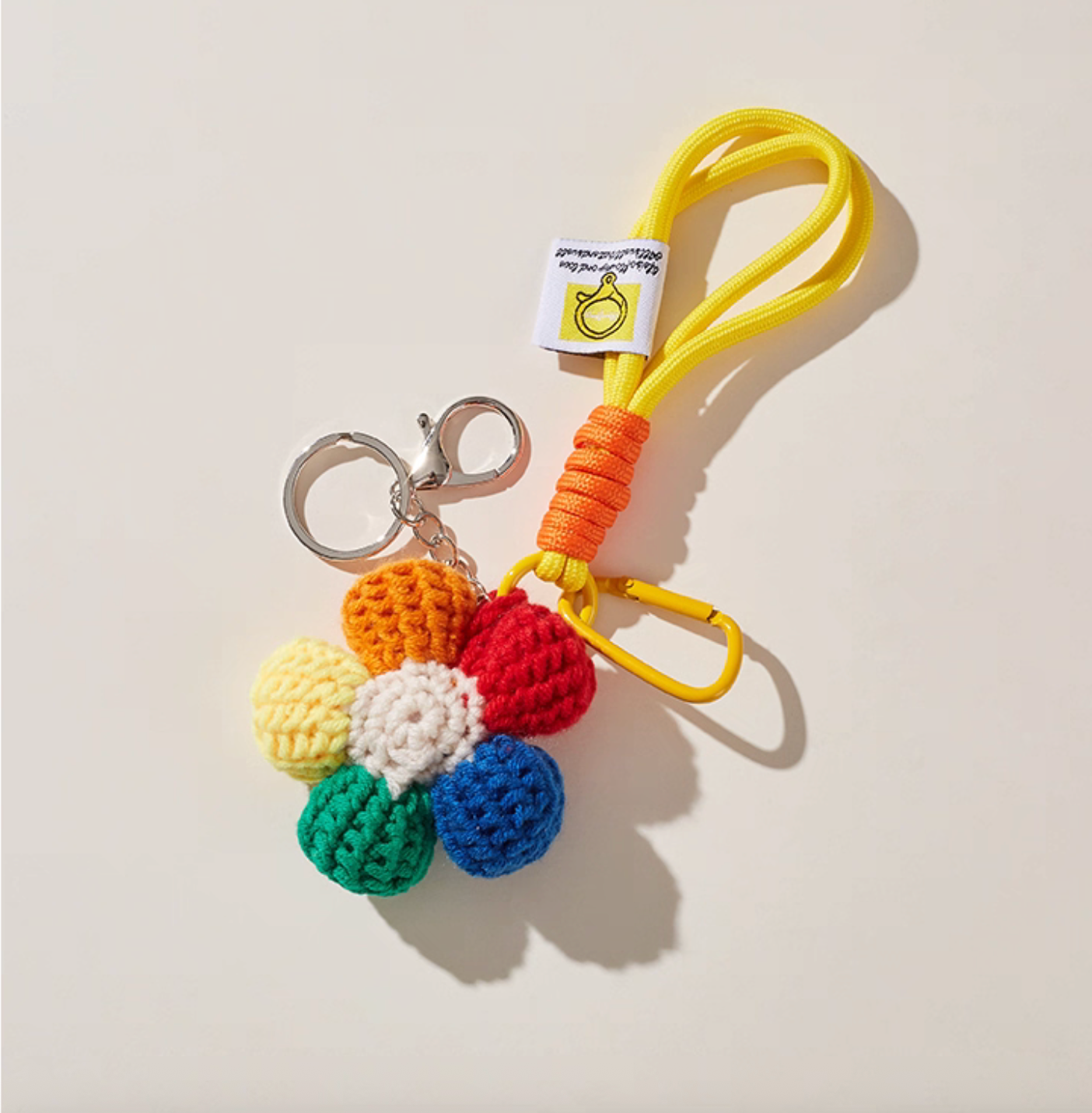 Handmade crochet daisy keychain with yellow cord loop, artisan-crafted.