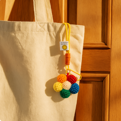 Crochet flower keychain hanging on a beige tote bag.