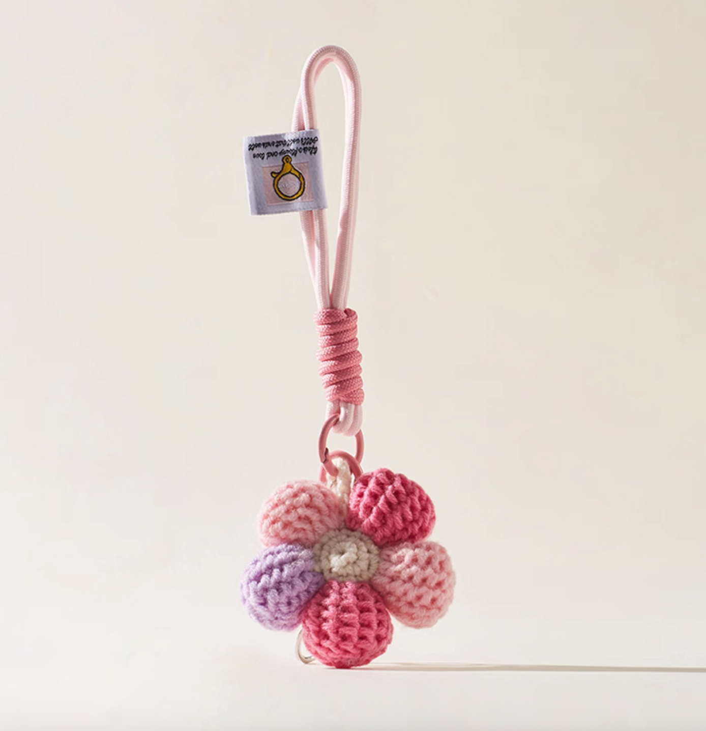Pink crochet daisy bag charm keychain with rope loop.