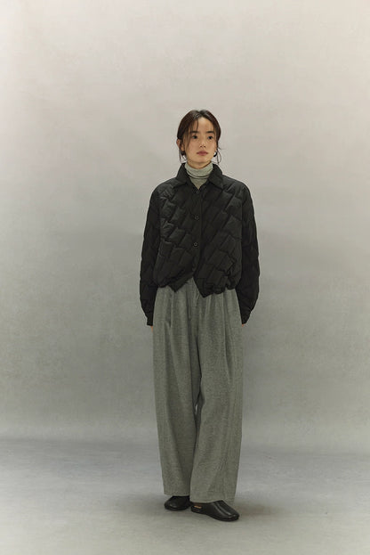 Full-body front view of black cropped quilted goose down shirt jacket with grey wide-leg pants and black shoes.