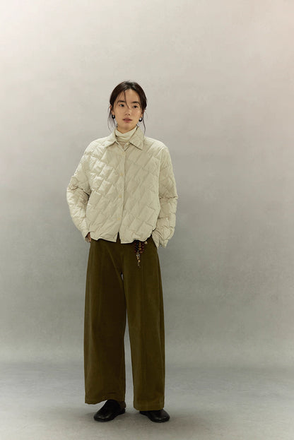 Woman wearing cream beige cropped quilted goose down shirt jacket with wide-leg olive pants, full front view.