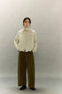 Woman wearing cream beige cropped quilted goose down shirt jacket with wide-leg olive pants, full front view.