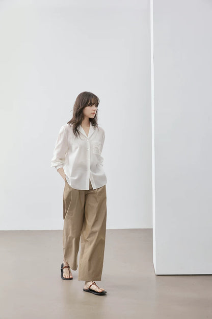 Woman wearing ivory Cuban collar shirt with khaki wide-leg trousers