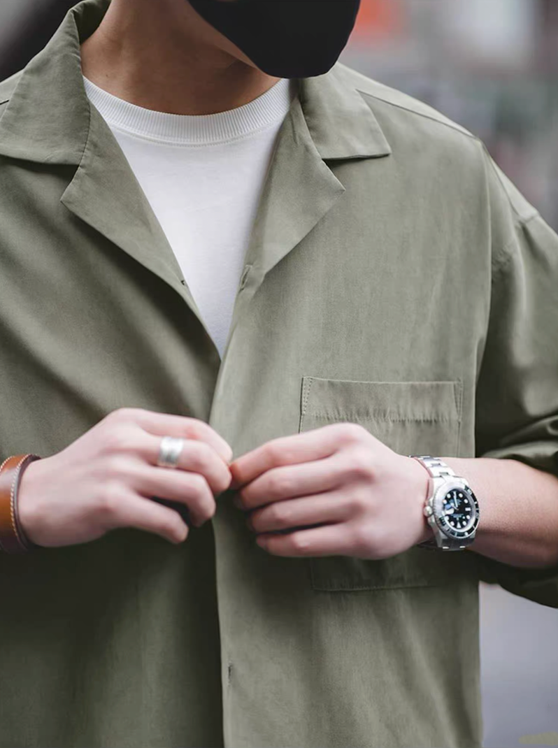 Close-up of Cuban collar shirt in light green, button detail.