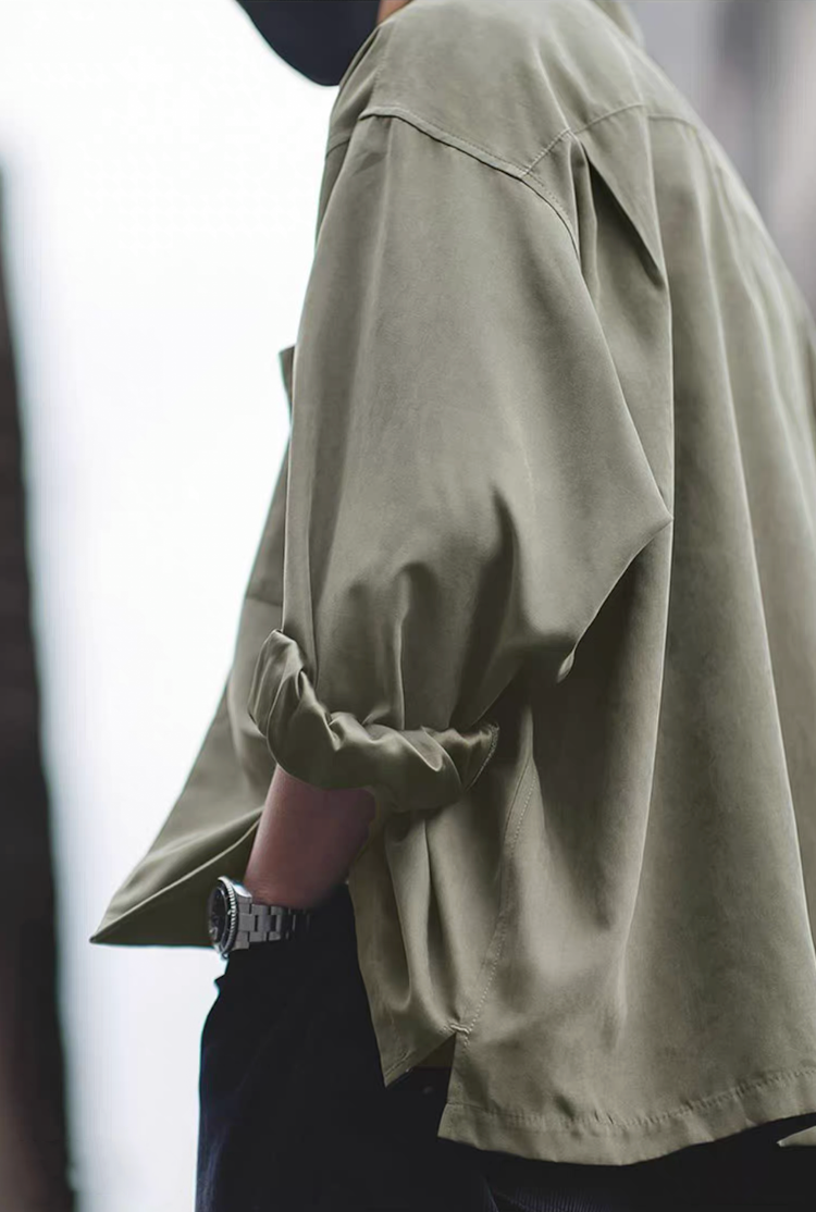 Side profile of light green Cuban collar shirt with rolled sleeves.