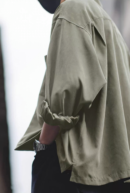 Side profile of light green Cuban collar shirt with rolled sleeves.