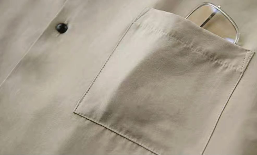 Detail of light khaki Cuban collar shirt chest pocket.