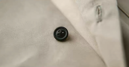 Close-up detail of button and stitching on light khaki Cuban collar shirt, highlighting craftsmanship and texture