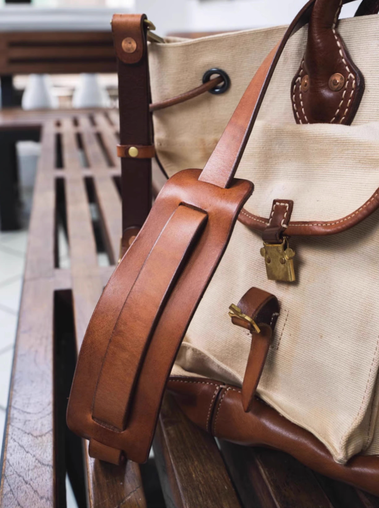 Adjustable leather shoulder strap and brass hardware on vintage canvas tote