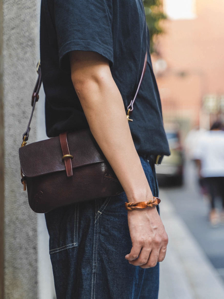 Side profile of dark brown Italian leather shoulder bag worn crossbody outdoors