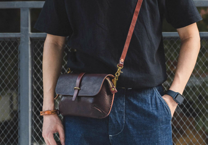Man standing wearing minimal Italian full-grain leather crossbody bag with brass hardware