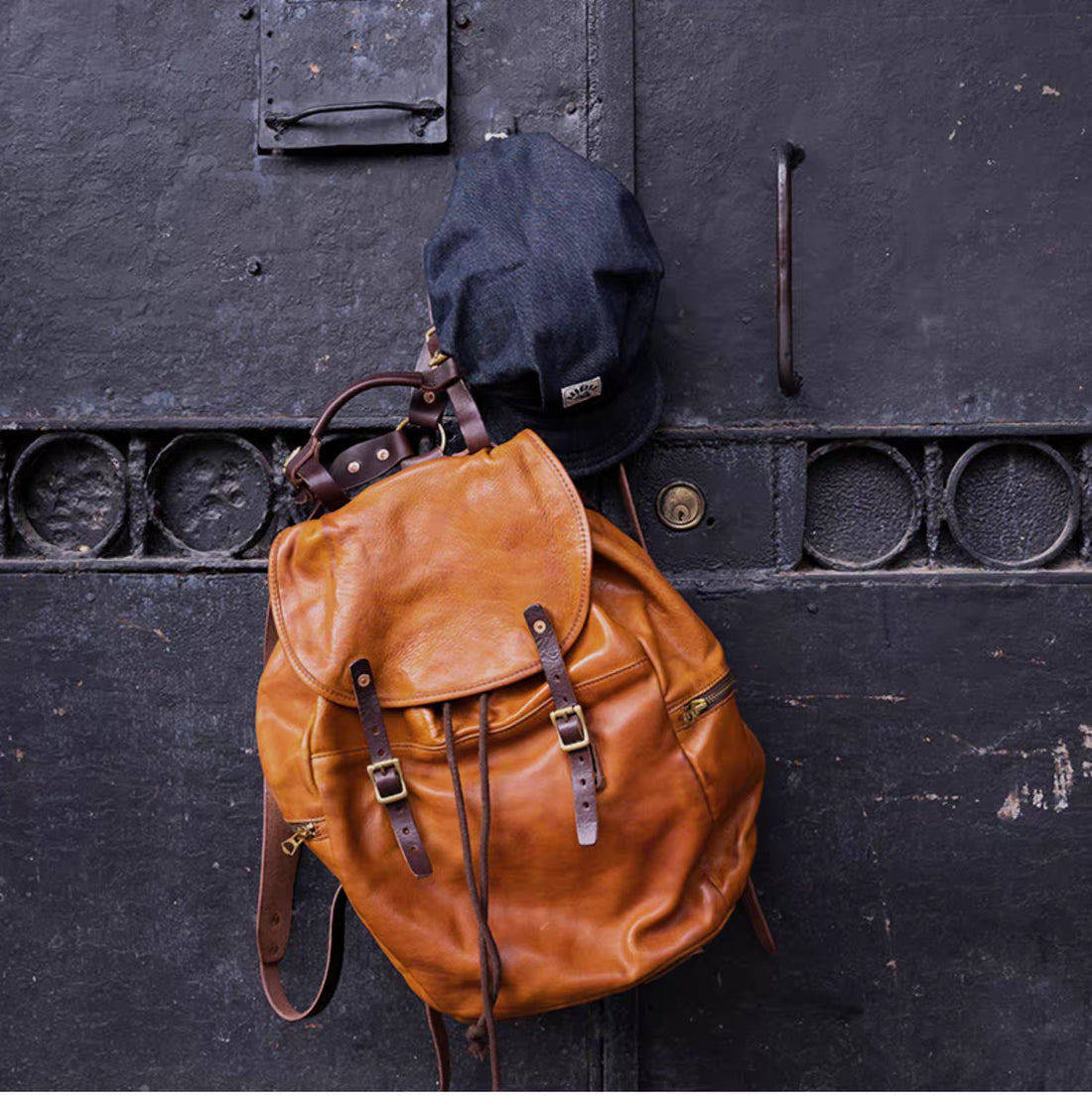 Vintage caramel brown Italian leather backpack hanging on an iron door