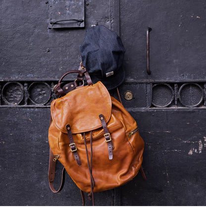 Vintage caramel brown Italian leather backpack hanging on an iron door