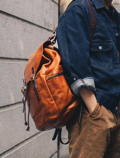 Man wearing handcrafted caramel brown full-grain leather backpack with brass hardware