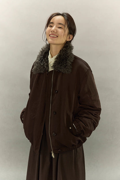 Smiling model in dark coffee brown sherpa-collar down jacket against neutral background
