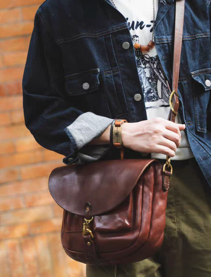 Man in denim jacket carrying vintage red-brown Italian leather crossbody bag
